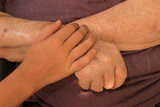 A young hand of a child touches and holds an old wrinkled hand