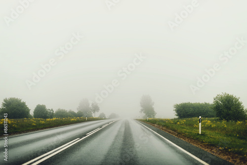 Empty foggy country road at summer.