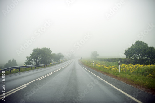 Empty foggy country road at summer.