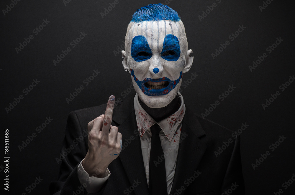 Terrible clown and Halloween theme: Crazy blue clown in black suit isolated on a dark background in the studio Terrible clown and Halloween theme: Crazy blue clown in black suit isolated on a dark background in the studio