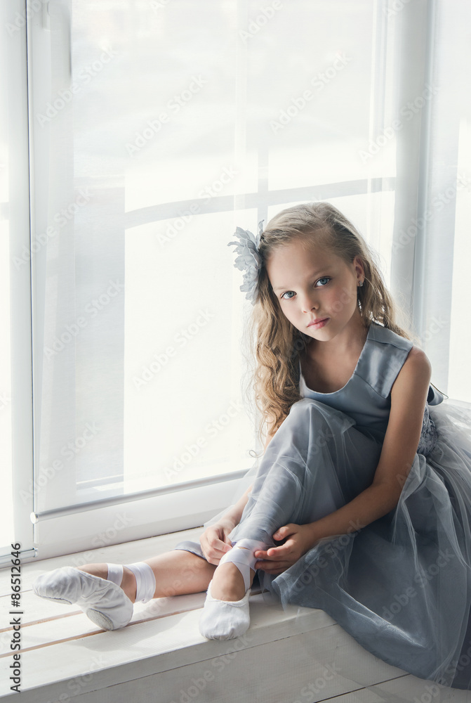 A little adorable young ballerina sitting on window A little adorable young ballerina sitting on window