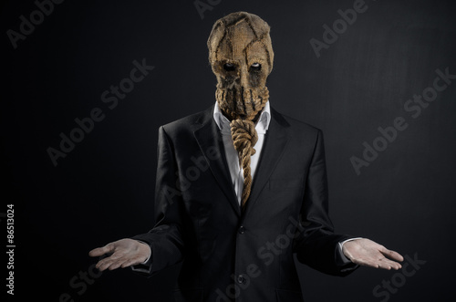 Fear and Halloween theme: a brutal killer in a mask on a dark background in the studio