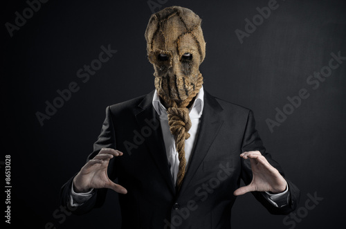 Fear and Halloween theme: a brutal killer in a mask on a dark background in the studio