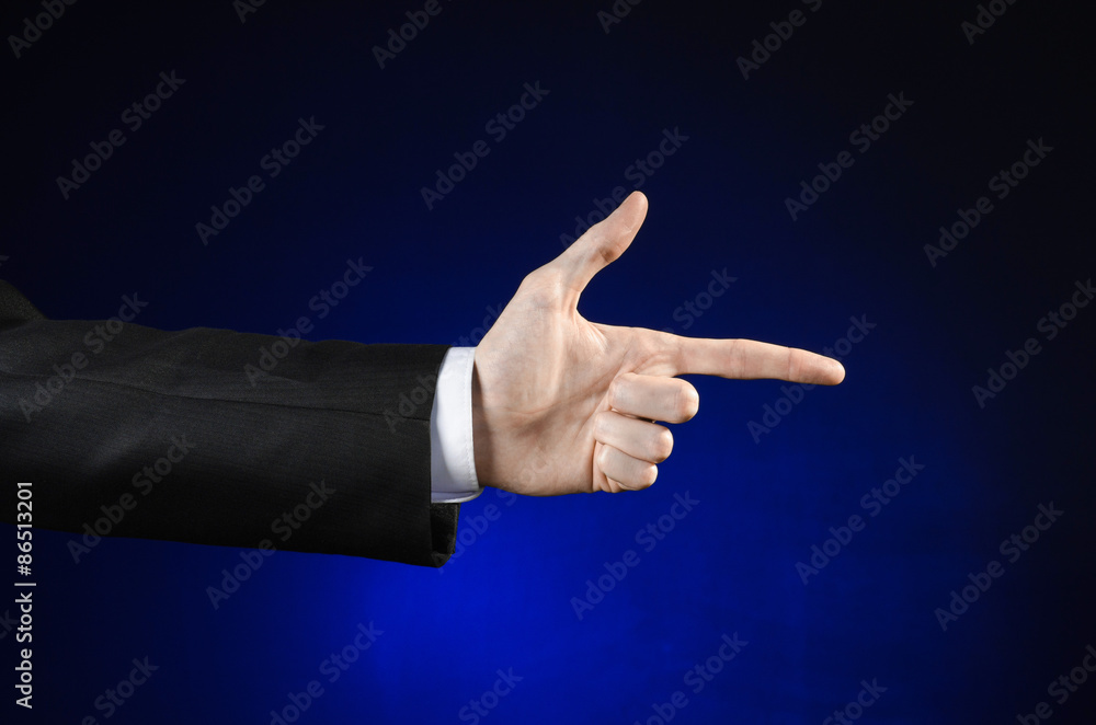 Businessman and gesture topic: a man in a black suit and white shirt showing hand gesture on an isolated dark blue background in studio Businessman and gesture topic: a man in a black suit and white shirt showing hand gesture on an isolated dark blue background in studio