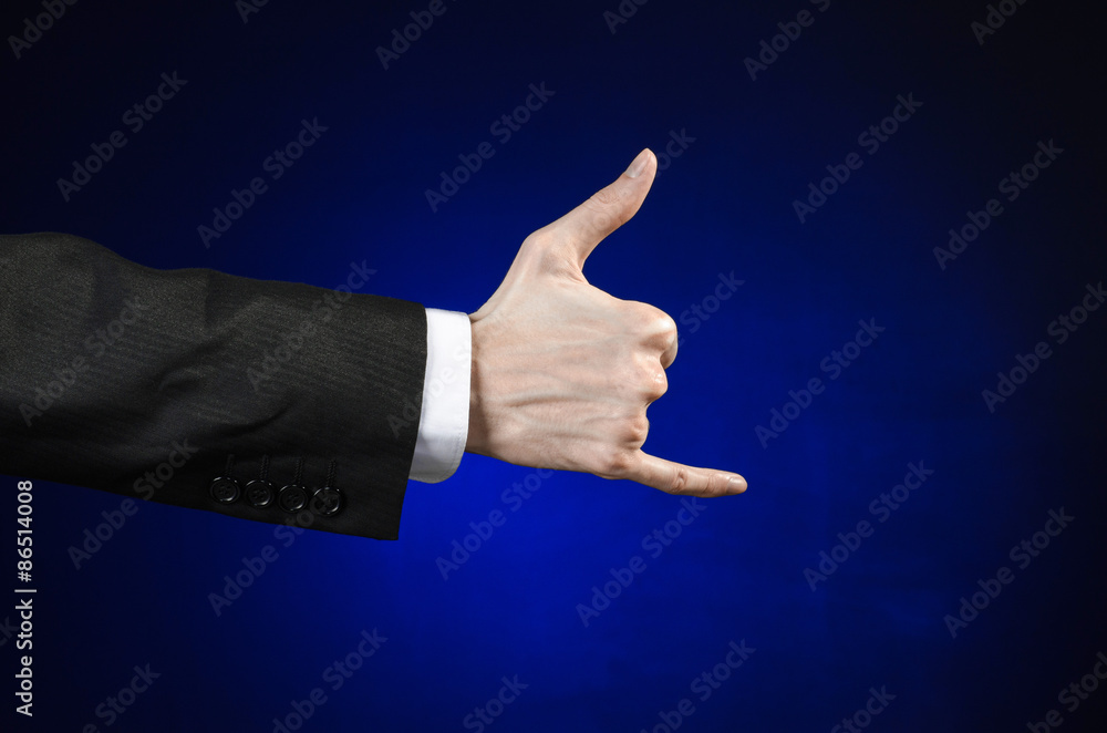 Businessman and gesture topic: a man in a black suit and white shirt showing hand gesture on an isolated dark blue background in studio Businessman and gesture topic: a man in a black suit and white shirt showing hand gesture on an isolated dark blue background in studio