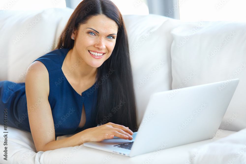 Young Woman Using a Laptop Computer While Relaxing at Home Young Woman Using a Laptop Computer While Relaxing at Home