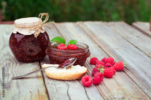 Raspberry jam and fresh raspberry on a rustic wooden table. DOF