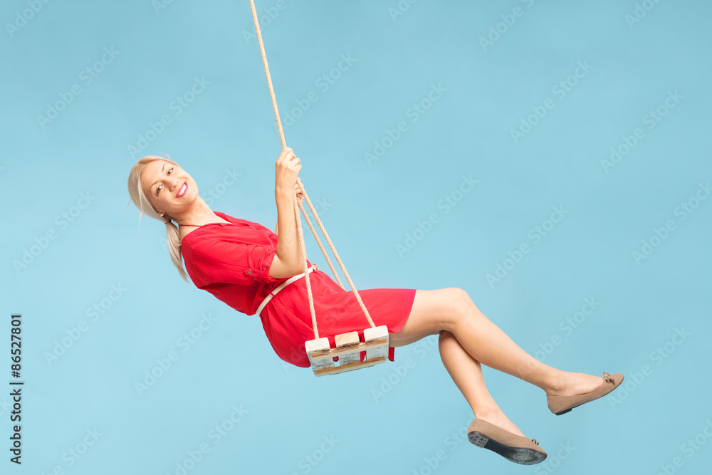 Carefree blond woman swinging on a swing - obrazy, fototapety, plakaty 