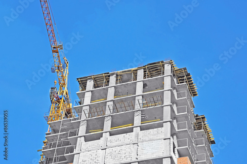 Crane and building construction site against blue sky