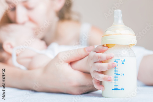 Baby holding a baby bottle with breast milk for breastfeeding. Mothers breast milk is the most healthy food for newborn baby.