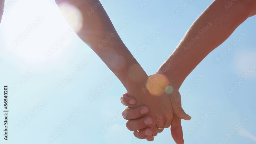 Close up of couple holding hands at the beach Close up of couple holding hands at the beach