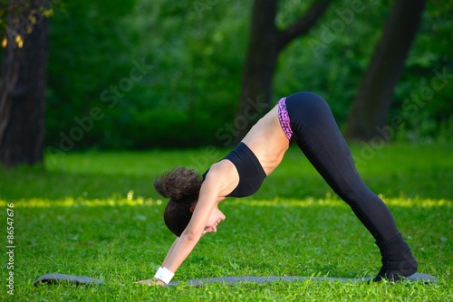 Sports girl does exercises workout outdoors in park