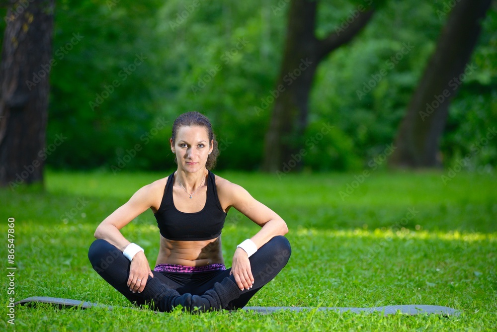 Sports girl does exercises workout outdoors in park