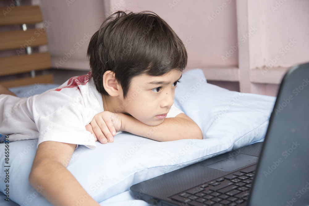 Little boy using notebook laptop in the bedroom Little boy using notebook laptop in the bedroom