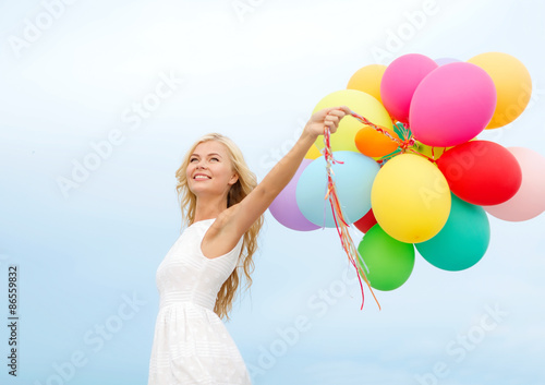 smiling woman with colorful balloons outside