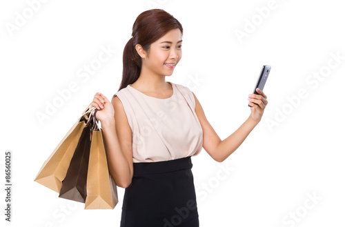 Young woman with shopping bag and using the mobile phone