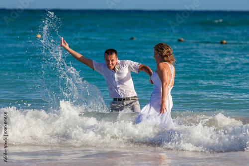 Young wedding couple have a fun in ocean waves