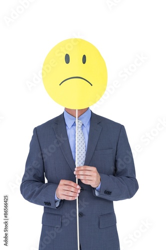  Businessman with sad smiley faced balloon at office desk