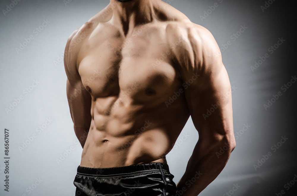 Muscular man posing in dark studio