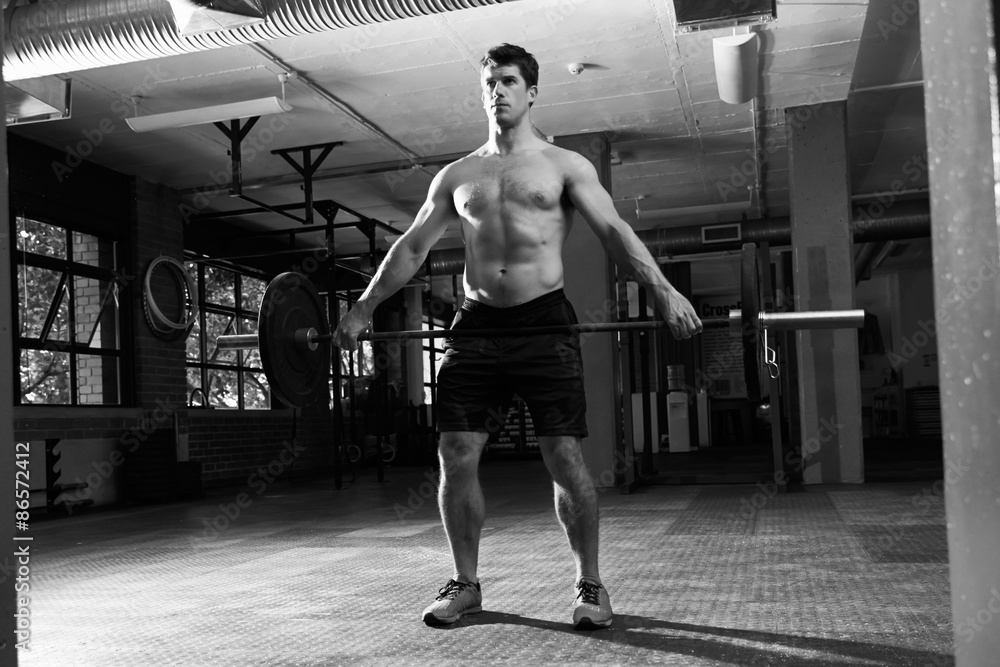 Fototapeta premium Black And White Shot Of Man In Gym Lifting Weights