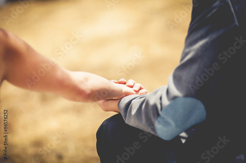 Close up of young loving couple holding hands. Vintage filter.