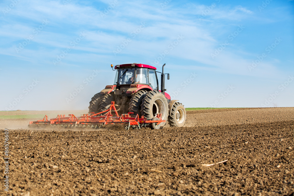 Obraz premium Farmer in tractor preparing land with seedbed cultivator