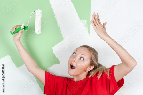 Happy woman in red t-shirt with paint roller in hand