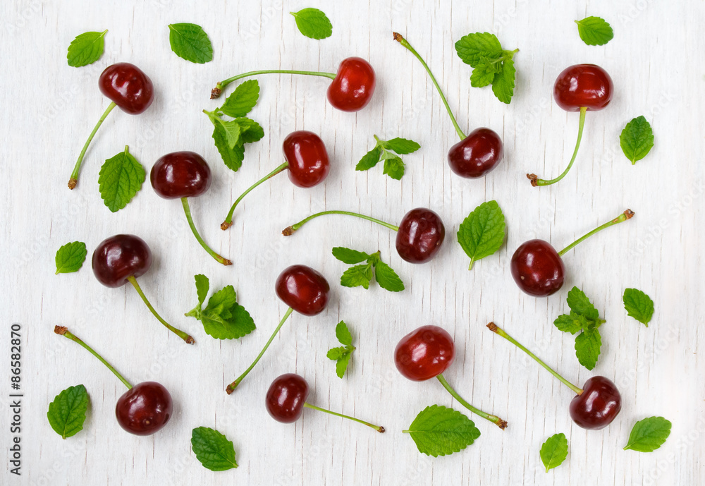 cherries and mint on a white wooden background. top view. cherries and mint on a white wooden background. top view.