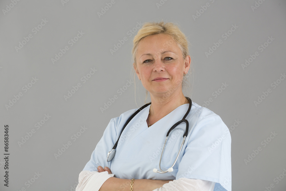Close up of blond female self confident doctor with crossed arms smiling and looking at the camera Close up of blond female self confident doctor with crossed arms smiling and looking at the camera