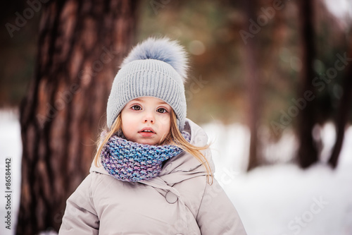 portrait of cute baby girl on winter walk in snowy forest
