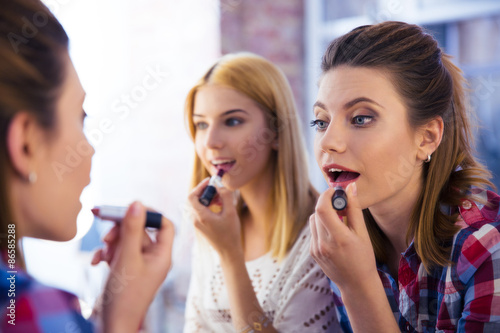 Two girl applying lipstick