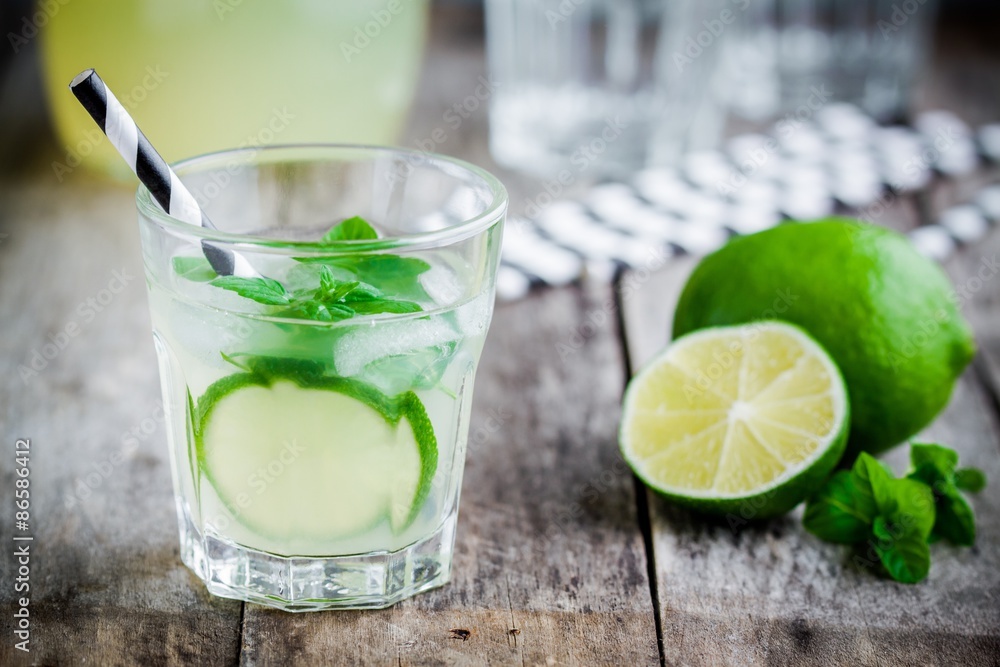 Fototapeta premium homemade lemonade with lime, mint and ice on a wooden table