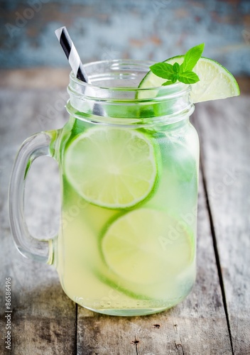 homemade lemonade with lime, mint in a mason jar on a wooden table