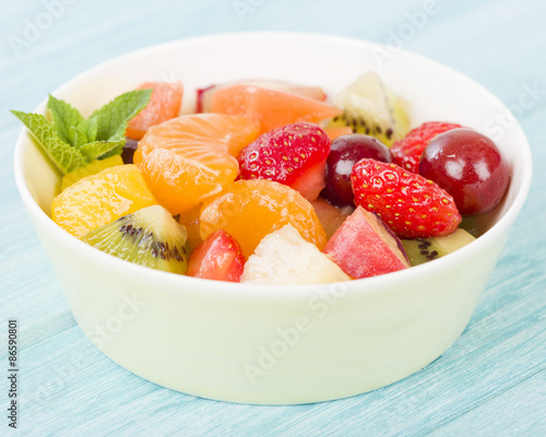 Fruit Salad - Bowl of fresh fruit salad on a blue background.