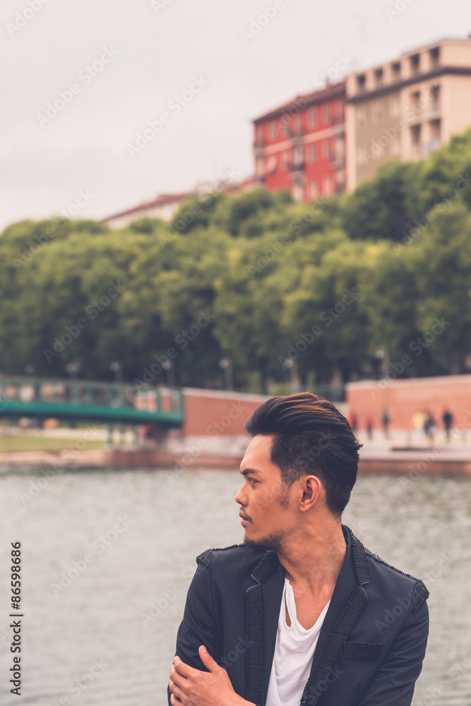 Handsome Asian model posing by an artificial basin Handsome Asian model posing by an artificial basin