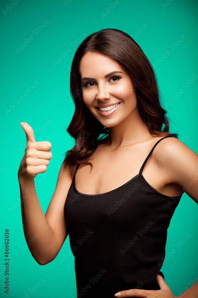 Fototapeta premium young woman showing thumb up hand sign gesture, over bright gree