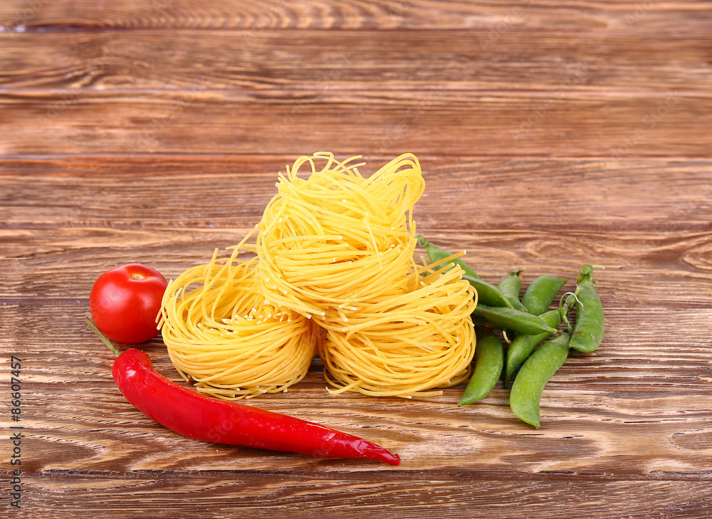 Pasta on the wooden background with tomato, peas and peppers Pasta on the wooden background with tomato, peas and peppers
