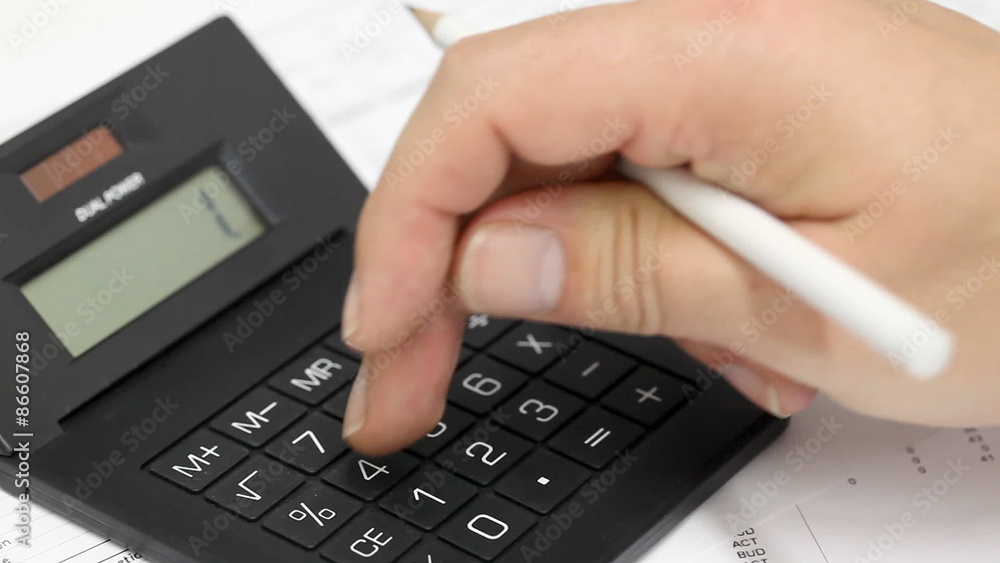 Business man checking numbers on calculator during finance check Business man checking numbers on calculator during finance check