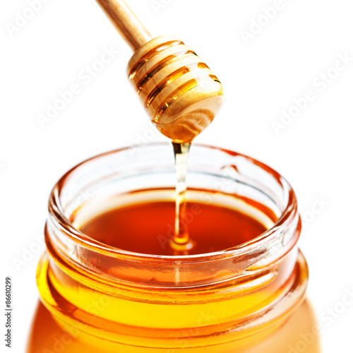 ..Honey Dipping with honey in glass jar isolated on white backgr