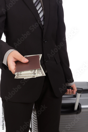 Business traveling pulling suitcase and holding passport