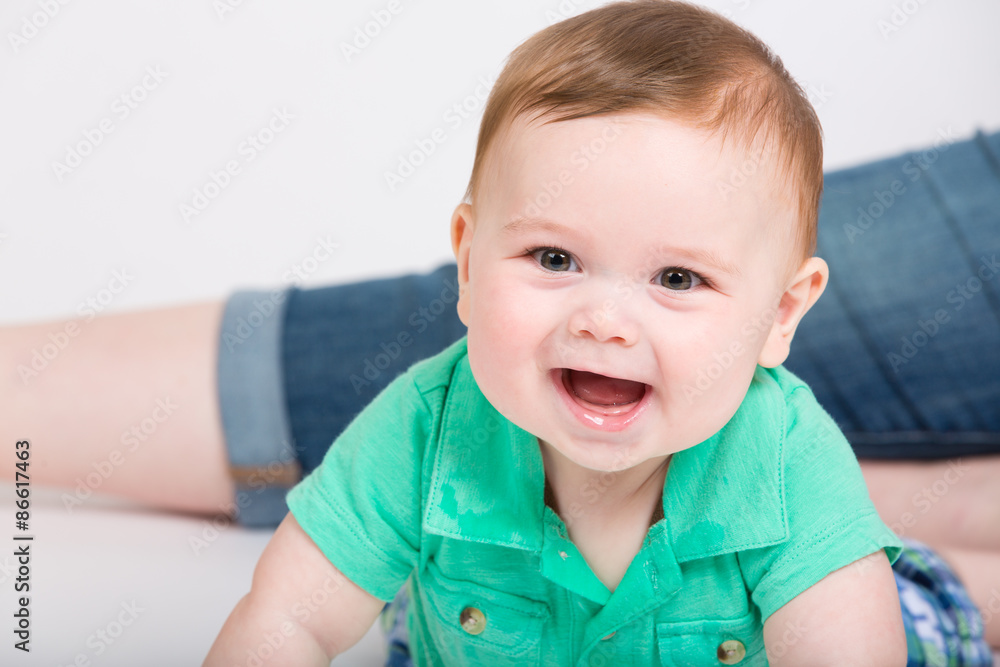 8 month year old baby lays on his stomach looking towards camera, while