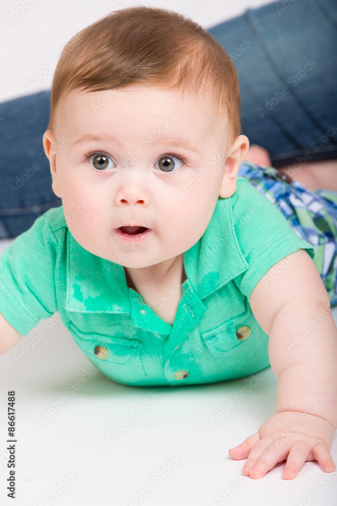 8 month year old baby lays on his stomach looking to the left, while