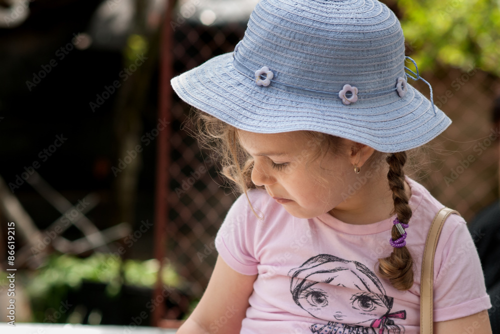 Beautiful little smiling girl sitting outdoors