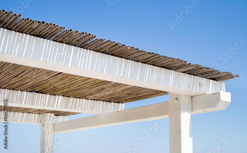 wooden and bamboo gazebo roof over summer blue sky © katrinshine