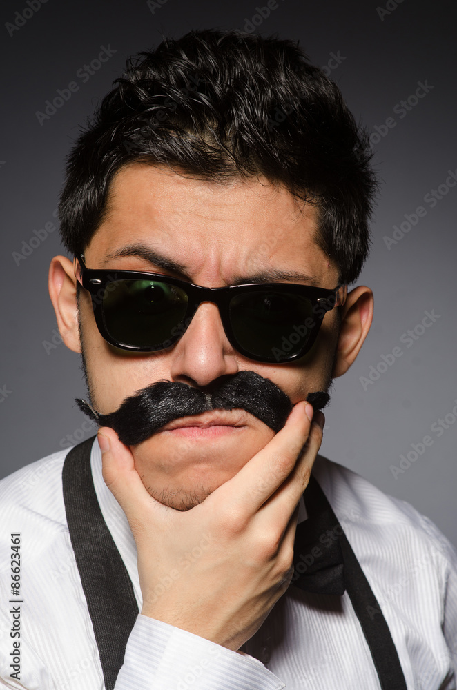 Fototapeta premium Young man with false moustache isolated on gray