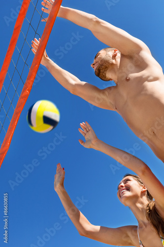 Happy young couple playing volleyball