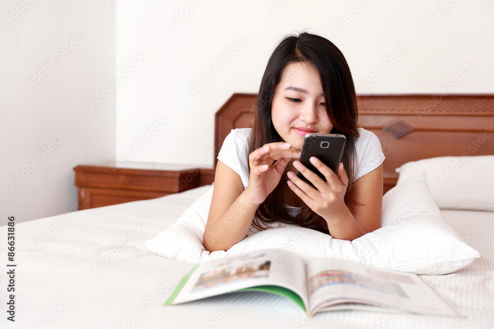 beautiful woman lying on the bed while playing mobile phone beautiful woman lying on the bed while playing mobile phone