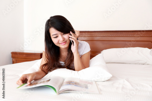 young woman enjoy reading a magazine while talking on the mobile