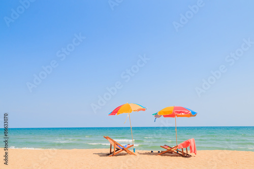 Blurred image of beach chair and umbrella on sand beach