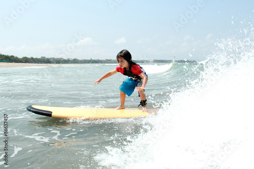 yooung boy learn to surf at ocean with splashing water